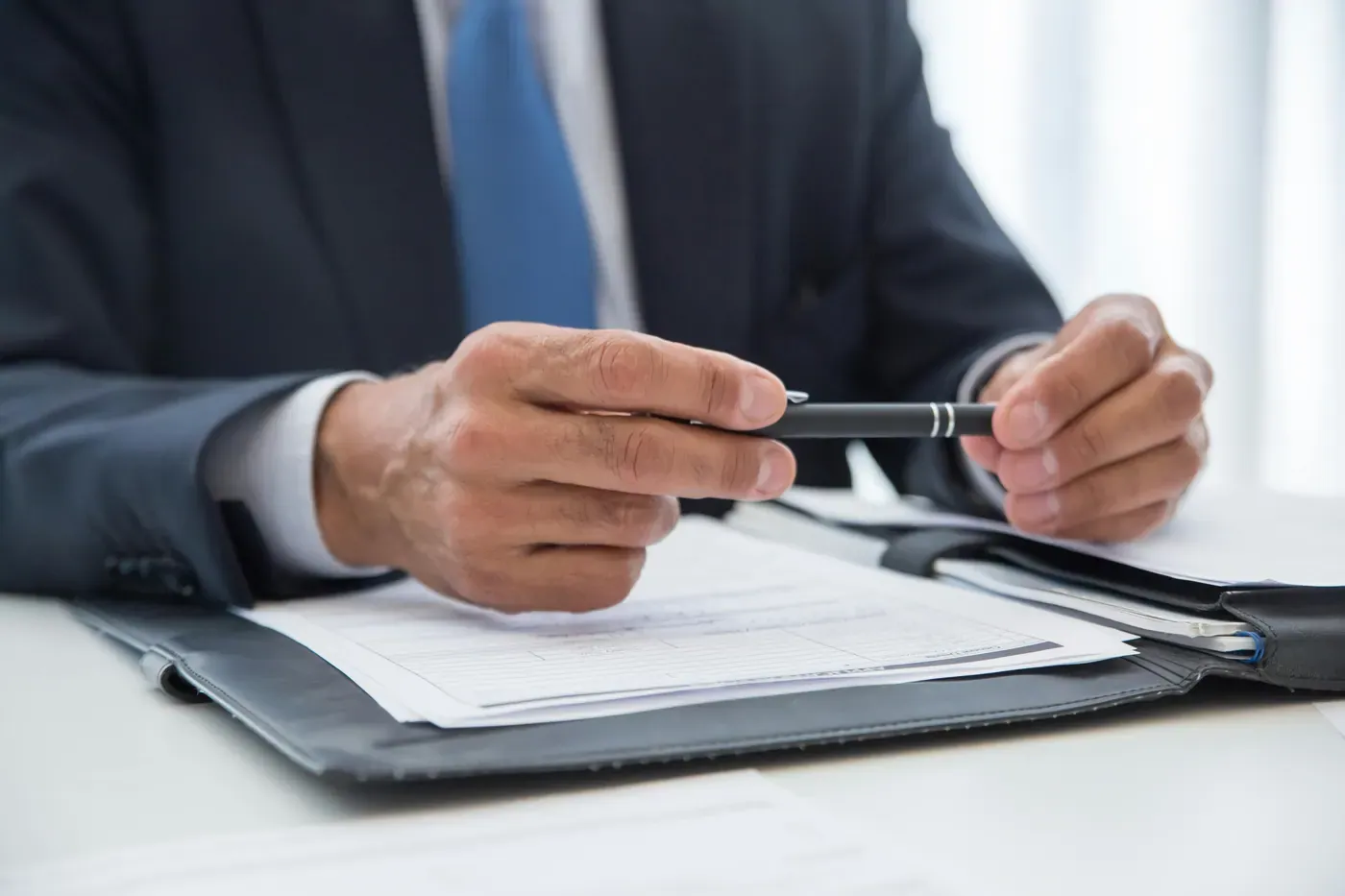 Executive writing with a fountain pen beside a leather briefcase