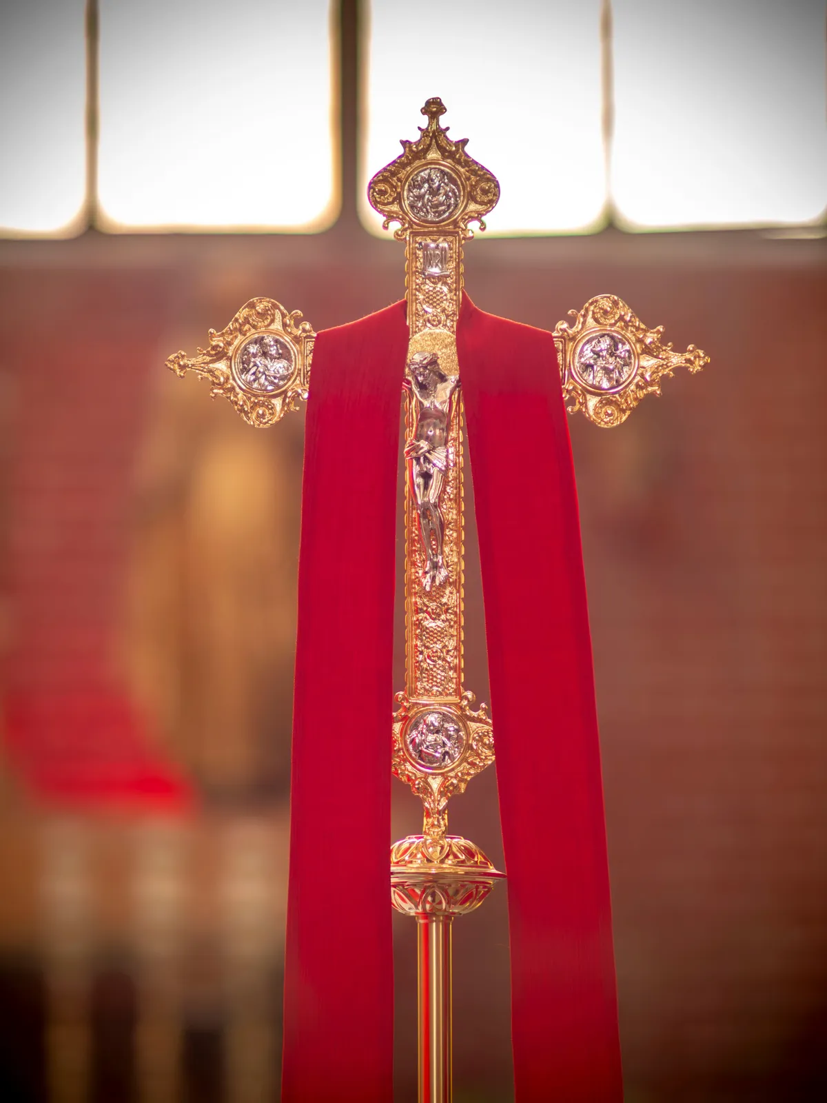 A processional crucifix carried before a red vestment.