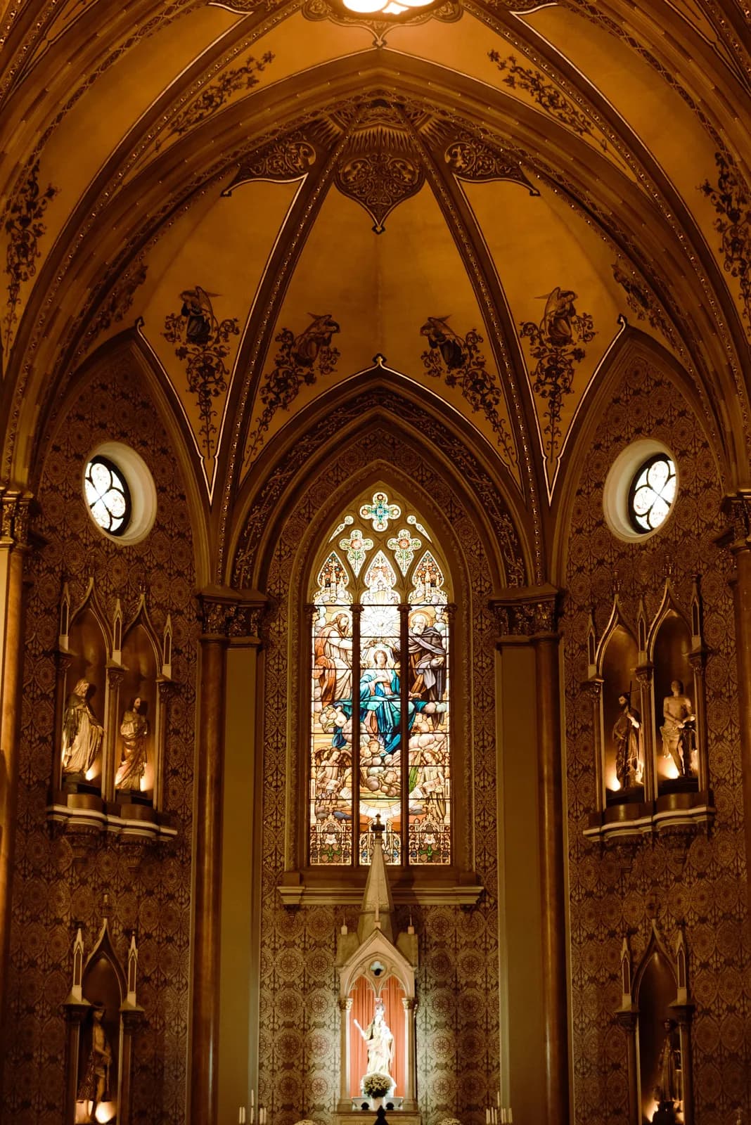 The interior of a Gothic chapel with stained-glass windows.