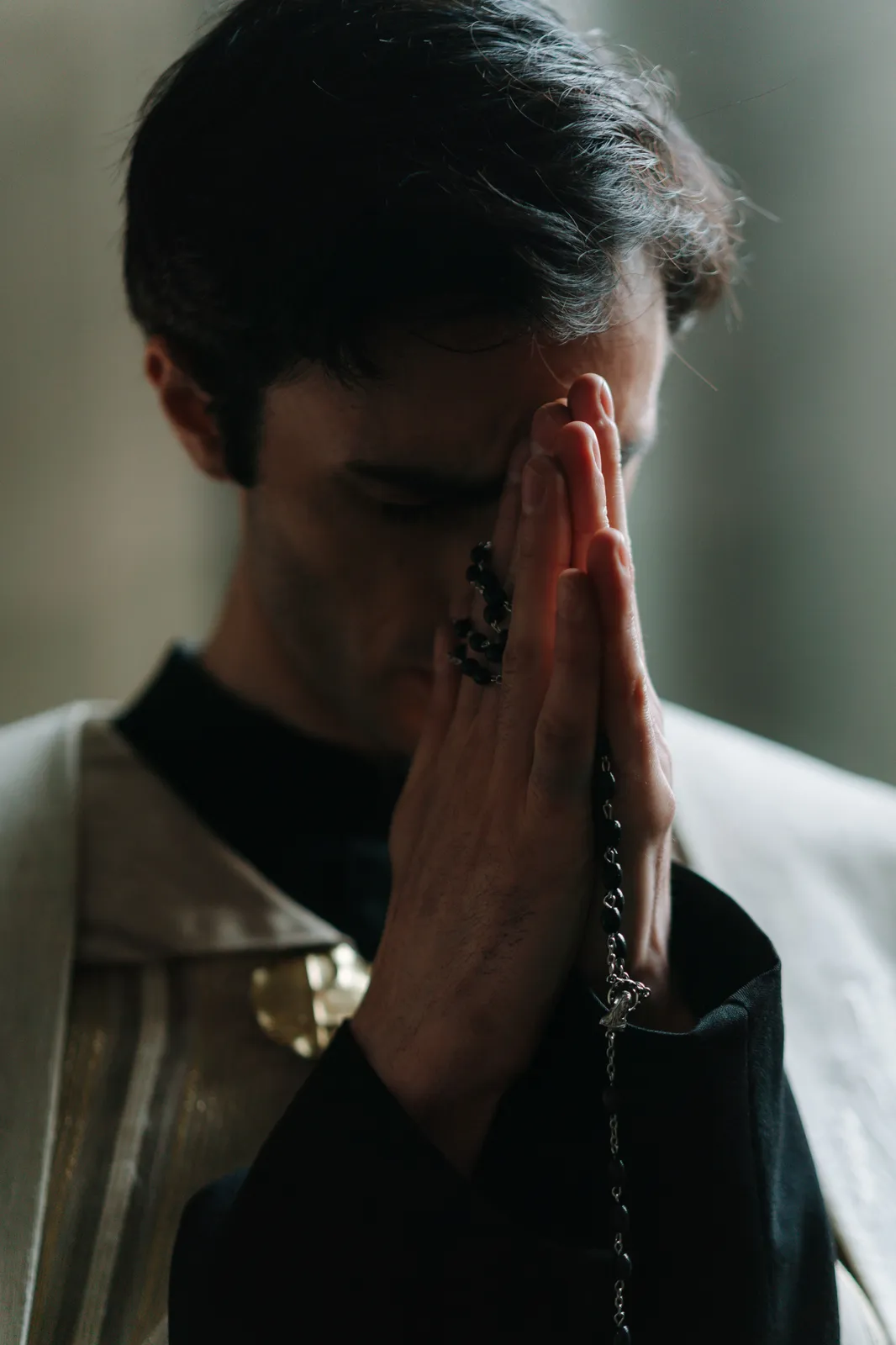 A man in quiet prayer, hands joined to his face.