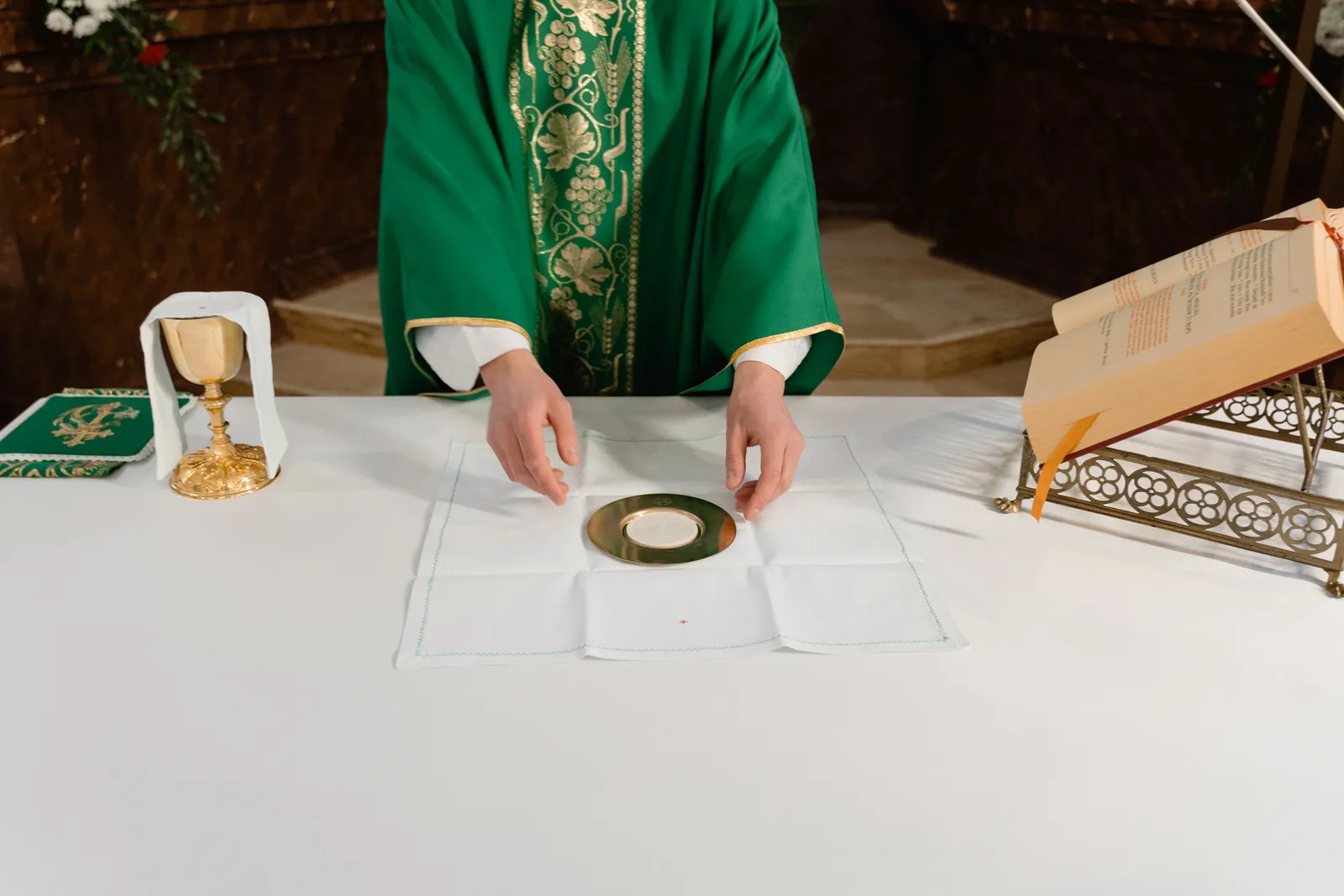 A priest preparing the host upon the corporal at the altar.