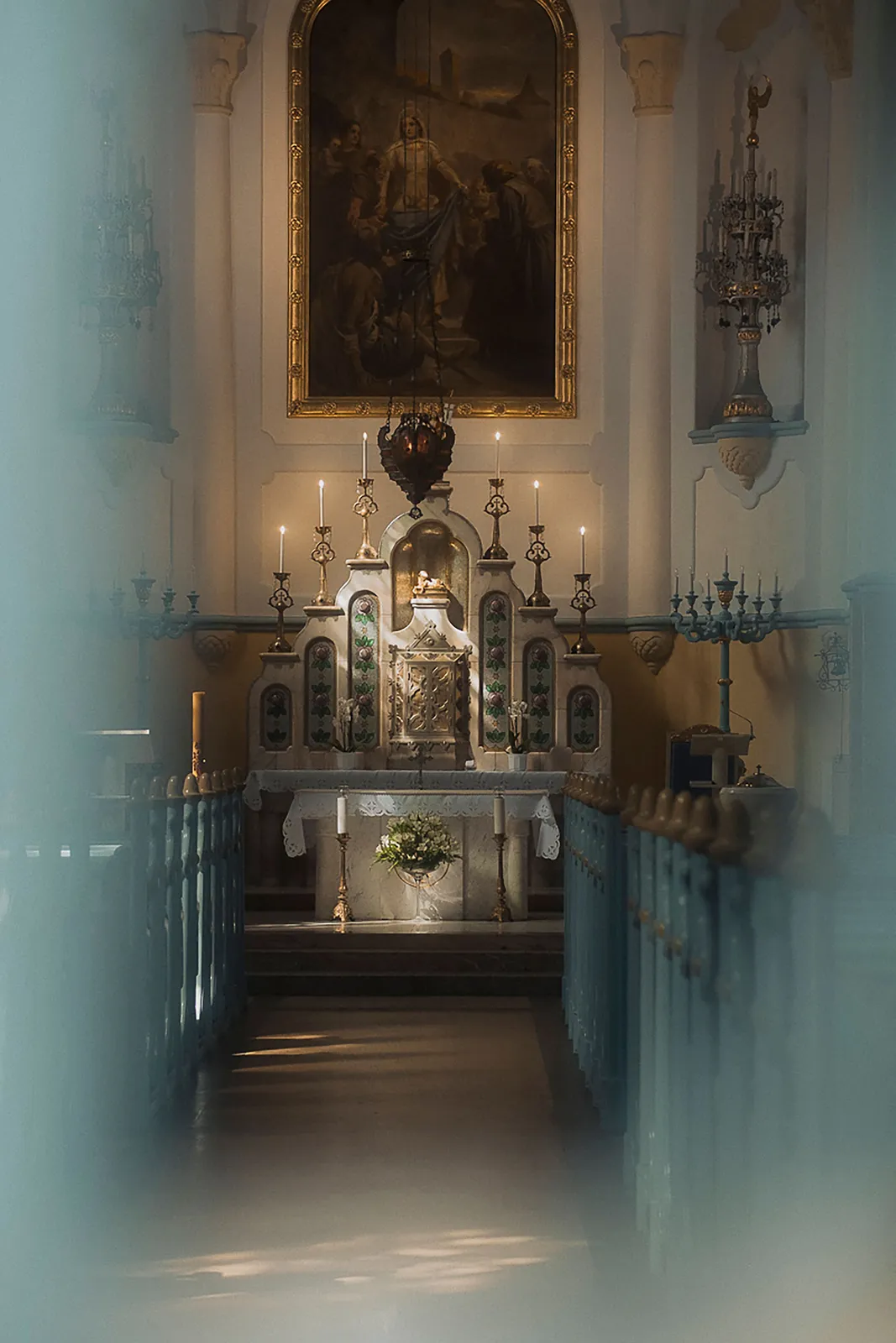 The candlelit interior of a church looking toward the altar.