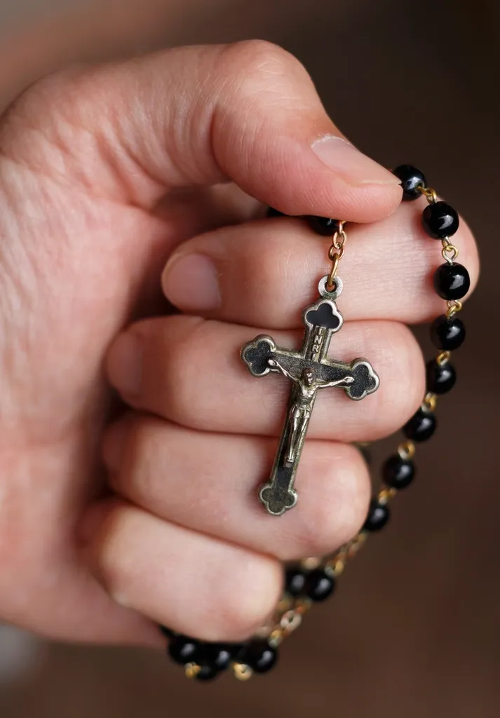 A hand holding a rosary with a crucifix.